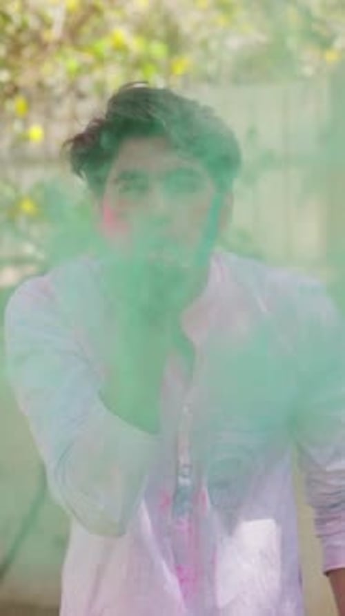 Vidéo verticale d'un Indien soufflant des couleurs de Holi devant la caméra