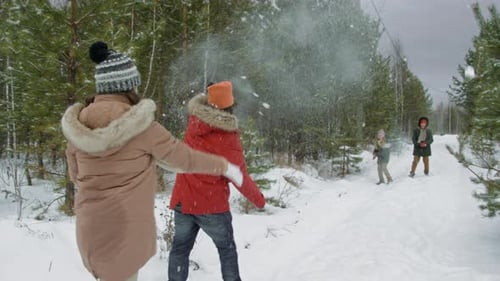 Mother and Father Having Fun Snowball Fight with Kids in Winter Forest