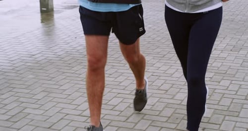 Fit, happy and mature couple jogging together along the ocean while talking