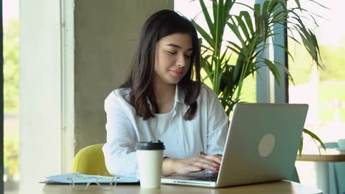 Smiling Girl Freelancer Chatting with Client While Resting at Cafe Using Laptop