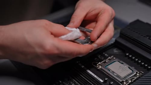 Hands cleaning CPU bracket before installing on motherboard