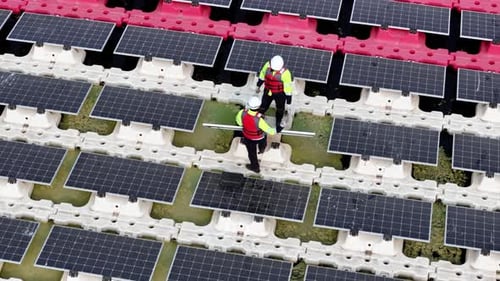 Photovoltaik-Technologie für grüne Energie, Arbeiter in einer Solaranlage. Luftaufnahme schwimmender Solarzellen.