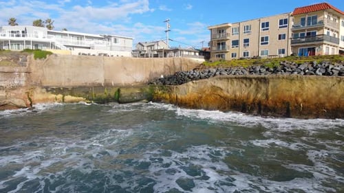 Foamy ocean waves hitting coastline of Sunset Cliffs in San Diego, aerial view
