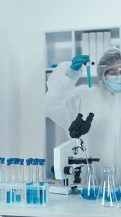 Wissenschaftler in Schutzanzug und Maske bei der Arbeit mit Reagenzgläsern in einem modernen Laborlabor