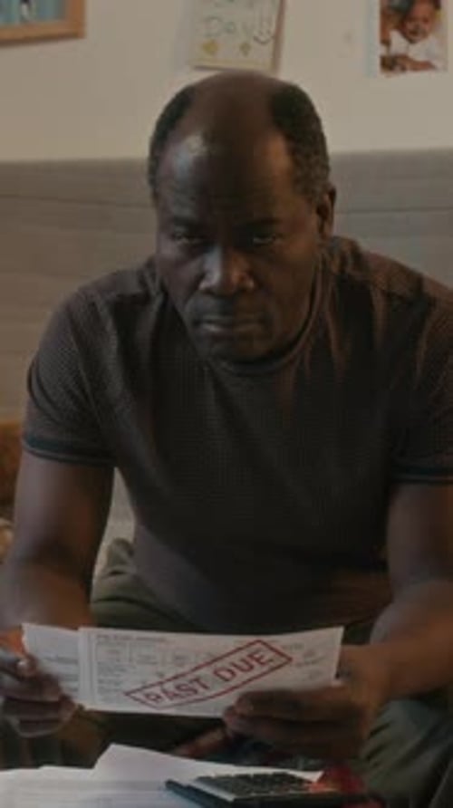 Portrait of Black Man Feeling Stressed About Past Due Bills, Looking at Camera