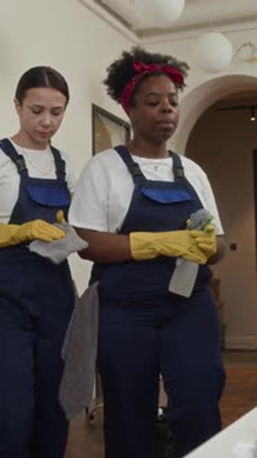 Female Cleaners Sharing Duties with Male Colleague Wiping Office Table