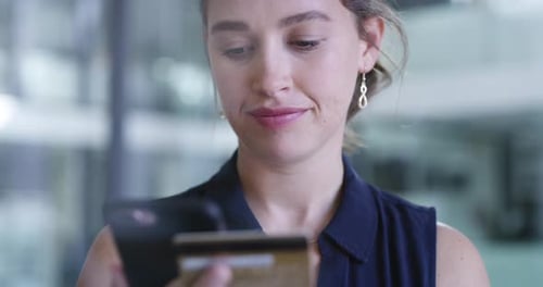 4k video footage of a young businesswoman using a cellphone and credit card in an office