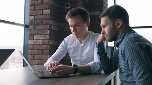 Drei junge Männer arbeiten mit ihrem Mentor über einen Laptop in einer Unternehmens- zusammen