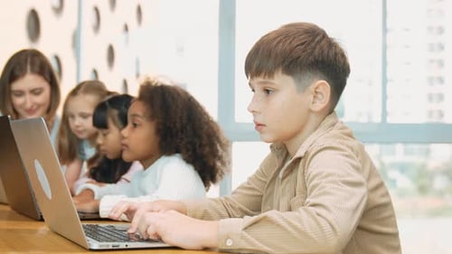 Smart boy playing laptop with multicultural friend learning prompt. Erudition.