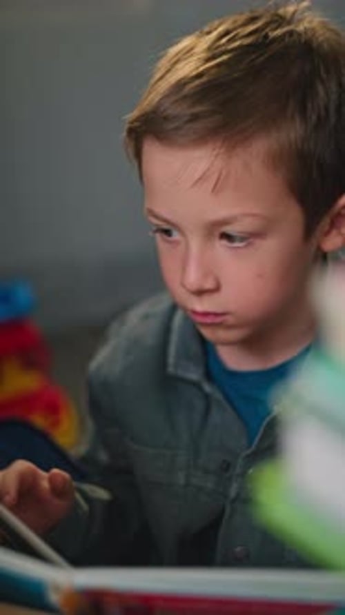 Elementary School Boy Reading a Textbook at Home