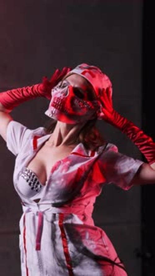 Beautiful sexy girl in scary nurse costume, red gloves and scary mask for Halloween on black backgro