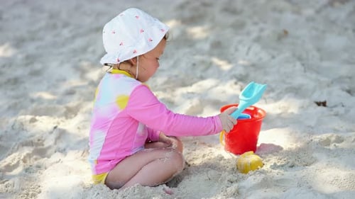 Little Girl Playing with Sand on Beach