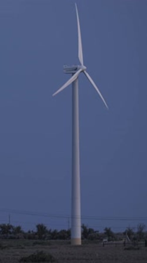 Wind Turbine Rotating in Rural Field at Night