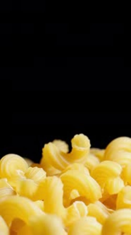Raw macaroni pasta falls gracefully in stunning slow motion.