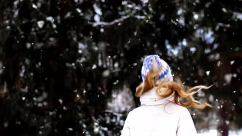 Cheerful woman enjoys winter season walking through snowy woods on christmas