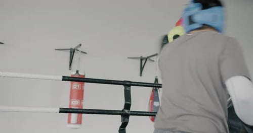 Professionelle Boxer, Männer mit Helmen und Handschuhen, trainieren im modernen Fitnessstudio und werfen Schläge