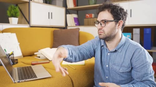 Man Works on Laptop During Video Conference