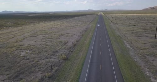 Drone — Highway in West Texas with mountains in background and car driving through