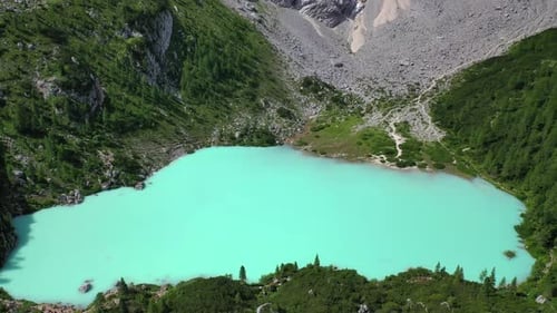 Lake Sorapis bright turqoise water in the Dolomites Italy, tilt up aerial