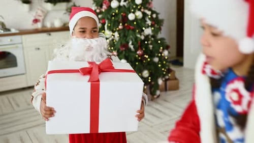 Boy and Girl Have Fun and Dance Holding a Christmas Present in Their Hands Against the Background of