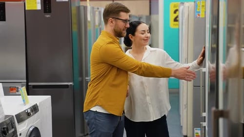 Couple Open Door of the Refrigerator in the Appliances Store and Compare with Other Models to Buy