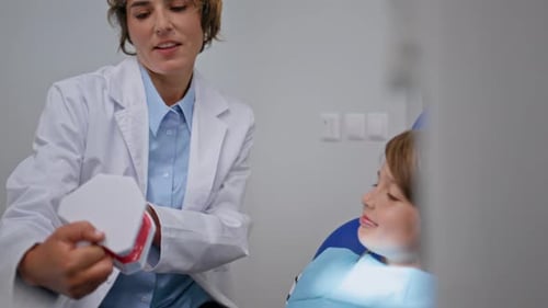 Dentist Teaching Child About Dental Hygiene in Office