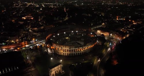 Aerial fly drone view of Colosseum or Coliseum at night, Rome, Italy, Europe. Ancient Roman ruin is