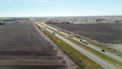 Mehrere Sattelzüge und Autos, die auf einer stark befahrenen Autobahn, umgeben von plattgepflügten Straßen, vorwärts fahren