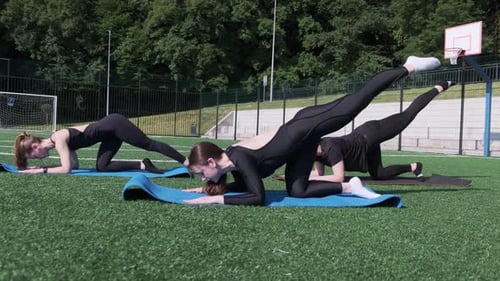 Athletic Women Doing Leg Lifts Outdoors on Field
