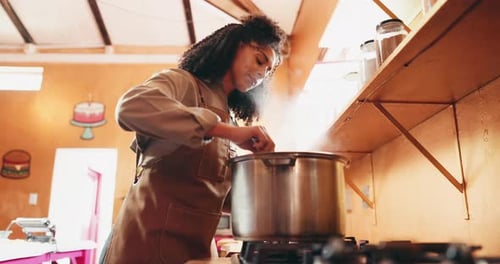 Woman Cooking in Kitchen, stirring a pot on stove