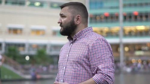 Worried man checks phone impatiently waiting on city street for meeting