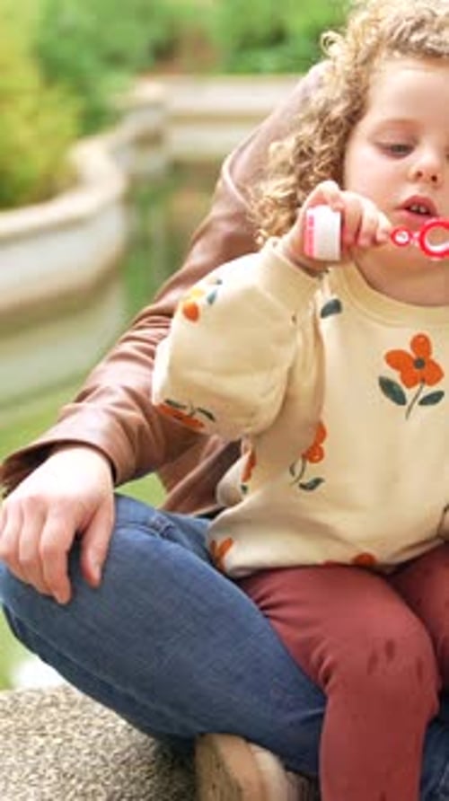 Mother and Girl Blowing Soap Bubbles in the Park