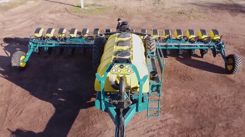 Blue tractor with yellow seeder working on the field in Ukraine OA