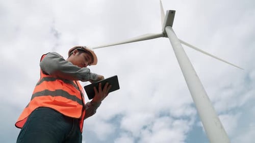 Progressive Engineer Working with the Wind Turbine with the Sky As Background