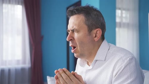 Coughing Man Sitting on Sofa in Living Room