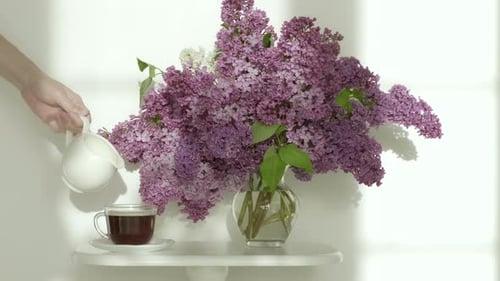 Milk Being Poured into Coffee Next to Lilacs