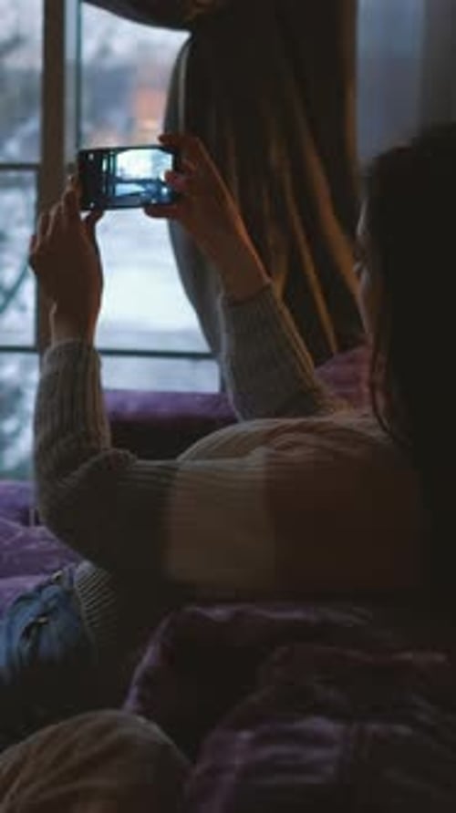 Woman Using Smartphone Lying on Couch by Window