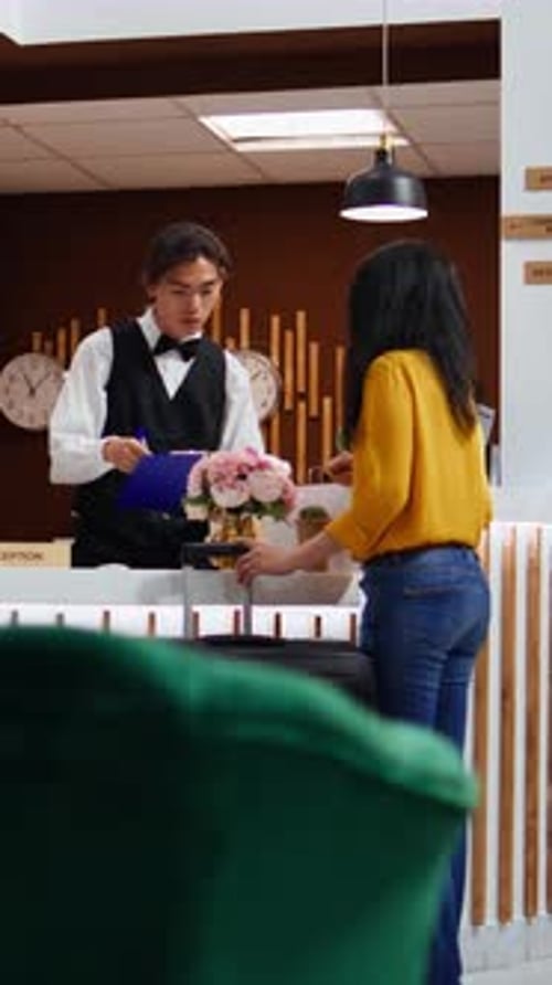 Woman Checking into Urban Hotel Front Desk
