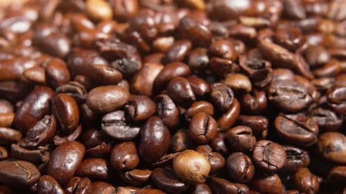 Extreme close-up of rotating roasted coffee beans filling the frame.
