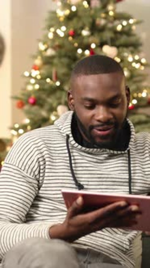 Young Handsome African Man in Casual Clothes Sitting on Sofa and Using New Digital Tablet on