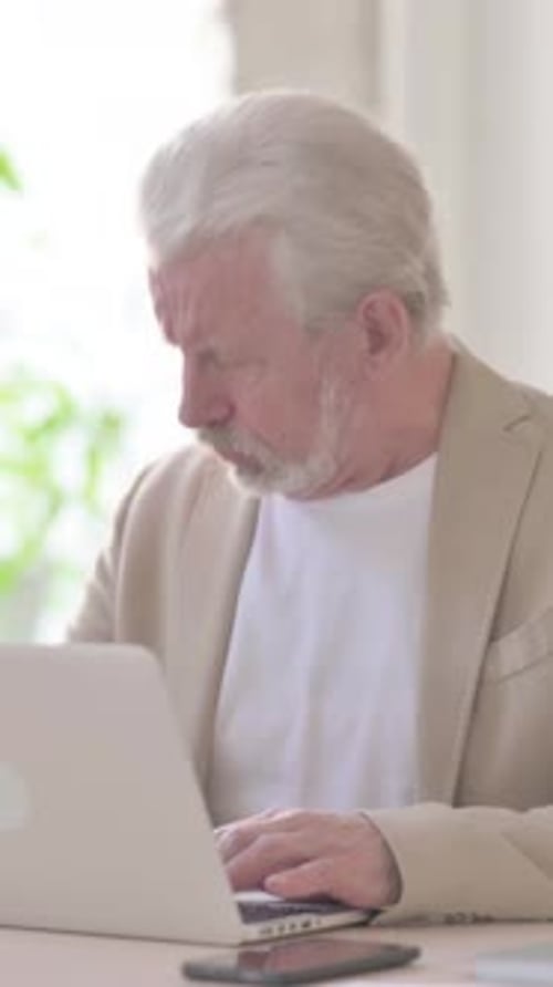 Old Man Coughing while using Laptop in Office, Vertical Video
