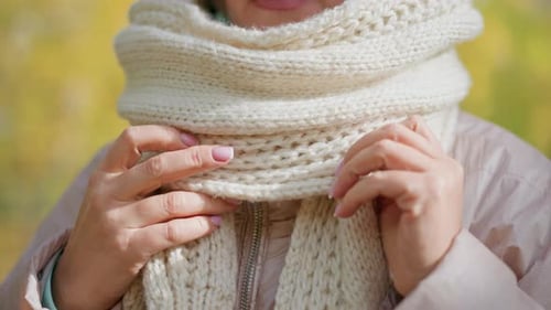 Woman Adjusting Chunky Knit Scarf Around Neck in Autumn Close Up