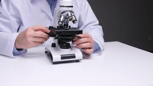 Scientist Adjusting Microscope in Lab