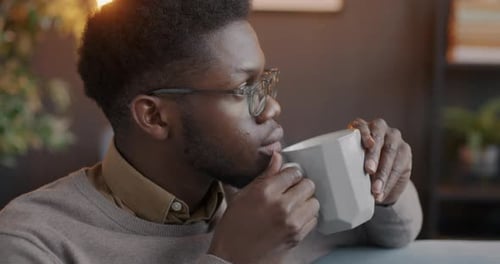 Young Adult Drinks from Mug Indoors
