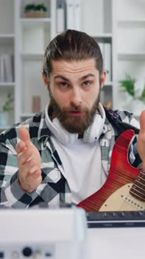 Man Holding Guitar and Talking in Bright Room
