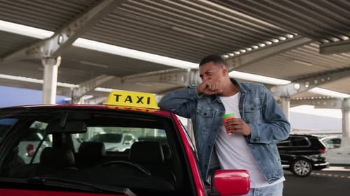 Man Leaning on Red Taxi in Parking Garage