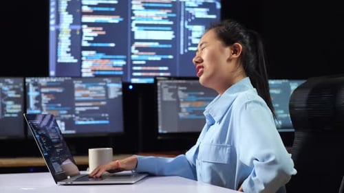 Side View Of Asian Female Programmer Having A Backache While Writing Code By A Laptop