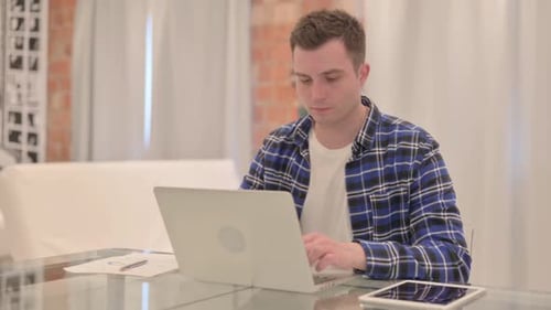 Young Adult Typing on Laptop at Desk