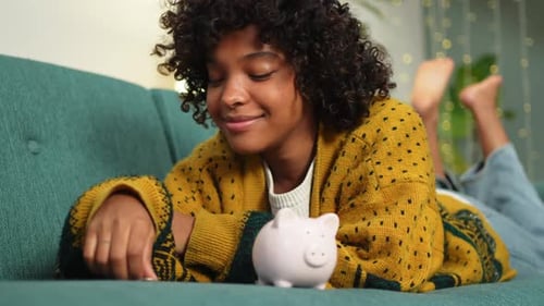 Saving Money Investment for Future African American Girl Putting Money Coin in Pink Piggy Bank