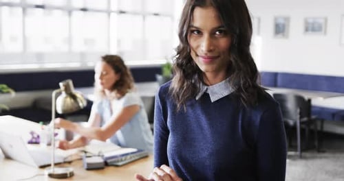 Portrait of happy biracial businesswoman smiling in modern office, slow motion
